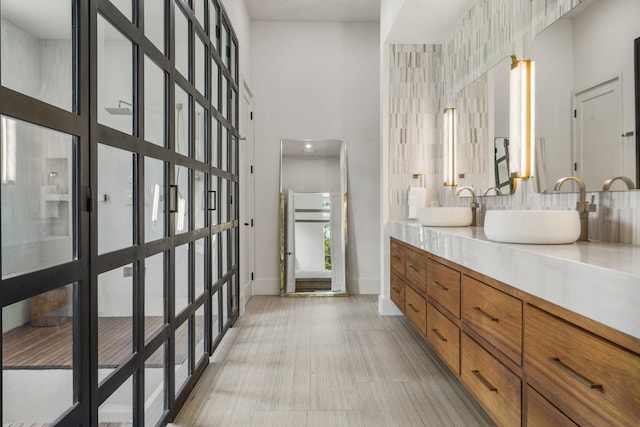 bathroom with tile walls, tile patterned flooring, vanity, and a high ceiling