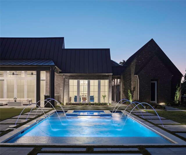 pool at dusk with an in ground hot tub and pool water feature