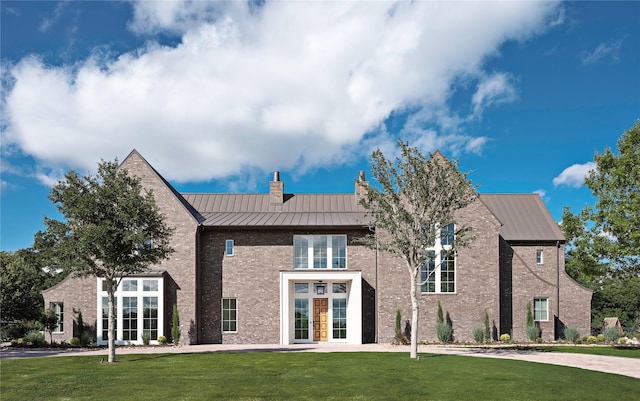 exterior space with a standing seam roof, brick siding, and a lawn