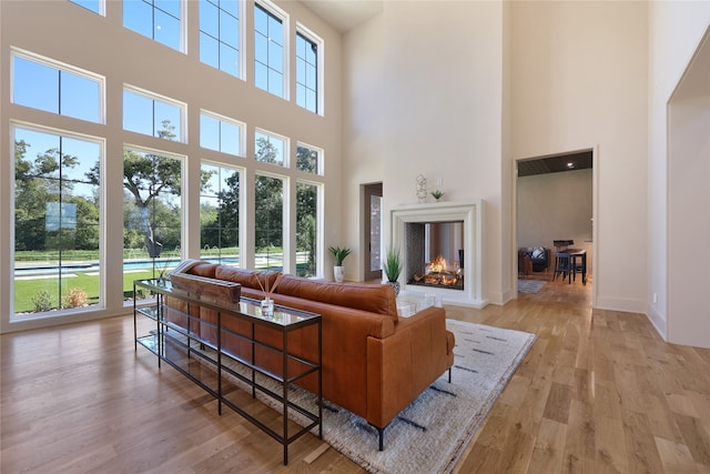 living room featuring a towering ceiling, light hardwood / wood-style floors, and a multi sided fireplace