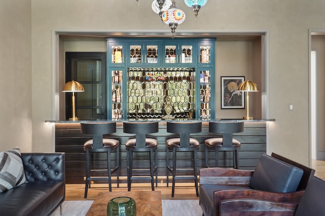 bar featuring light hardwood / wood-style floors and blue cabinetry