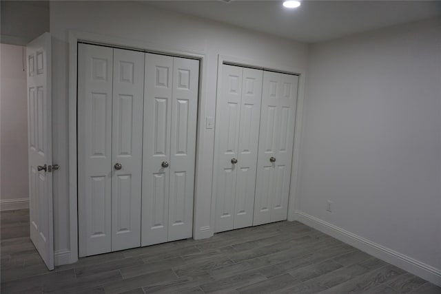 unfurnished bedroom with hardwood / wood-style floors and multiple closets