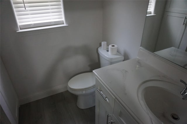 bathroom featuring baseboards, wood finished floors, toilet, and vanity