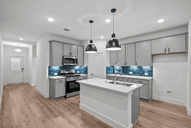 kitchen with stainless steel appliances, a sink, and gray cabinetry