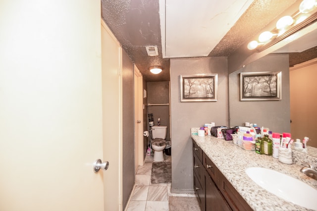 bathroom featuring tile patterned flooring, toilet, a textured ceiling, and vanity