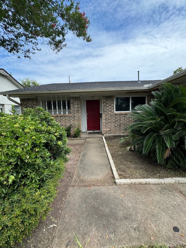 view of front of home with a shingled roof and brick siding