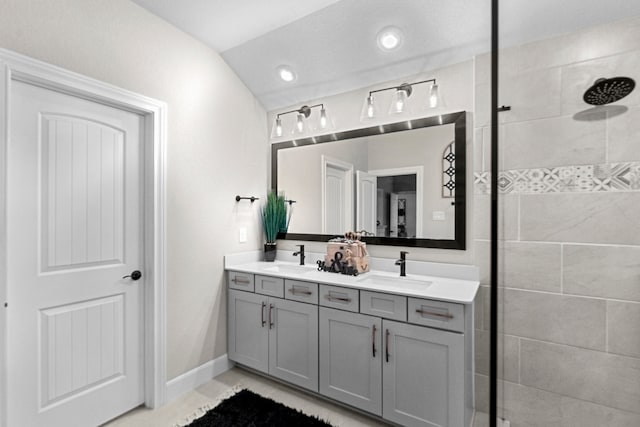 bathroom with vaulted ceiling, tile patterned flooring, double sink vanity, and a tile shower