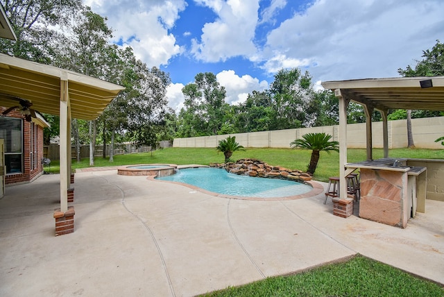 view of swimming pool featuring a lawn, a patio, and an in ground hot tub