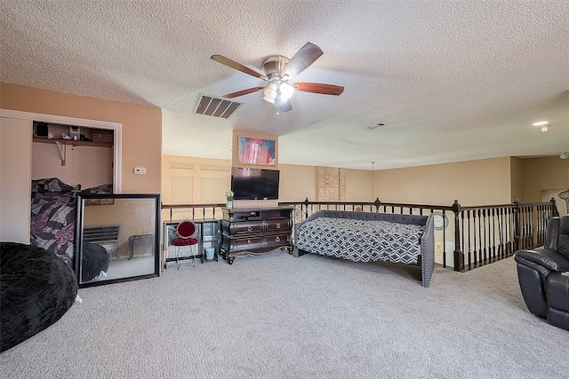 carpeted bedroom with ceiling fan and a textured ceiling