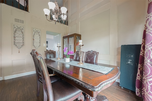 dining space featuring dark hardwood / wood-style flooring, a notable chandelier, and a high ceiling