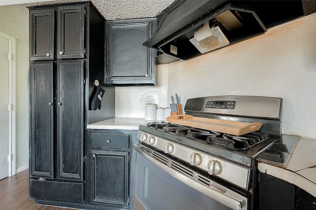 kitchen featuring custom range hood, a textured ceiling, gas range, and wood-type flooring