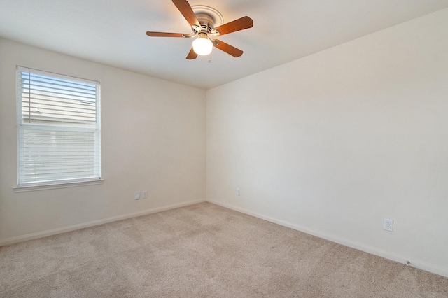 unfurnished room with a ceiling fan, light colored carpet, and baseboards