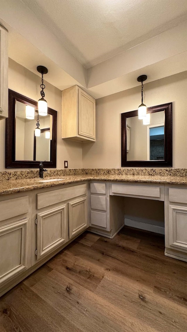 kitchen with light stone countertops, built in desk, sink, and dark hardwood / wood-style flooring