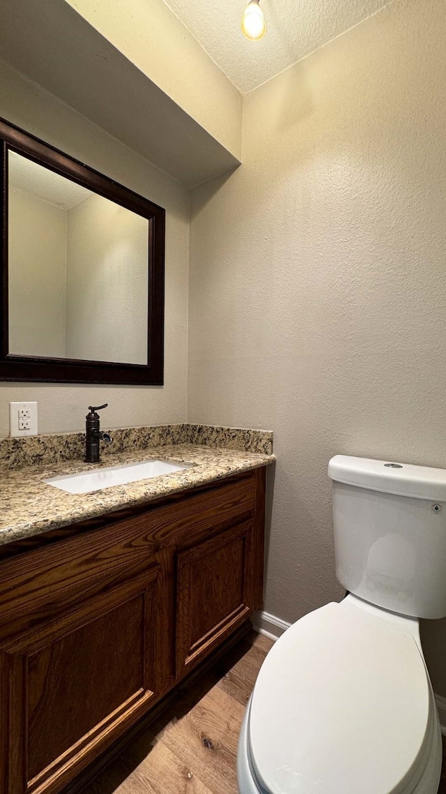 bathroom featuring a textured ceiling, toilet, vanity, and wood-type flooring