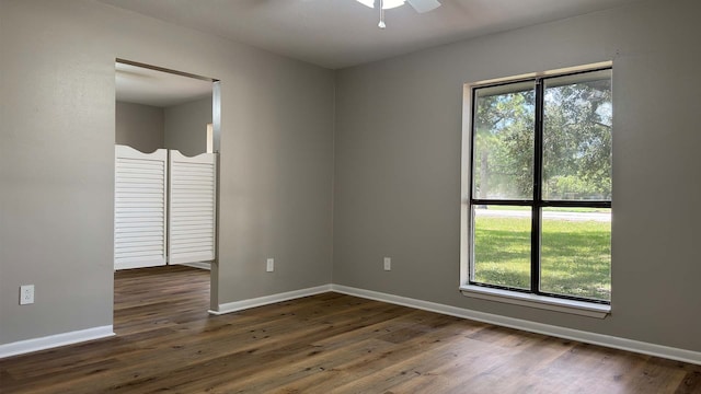 empty room featuring ceiling fan, dark hardwood / wood-style floors, and a healthy amount of sunlight