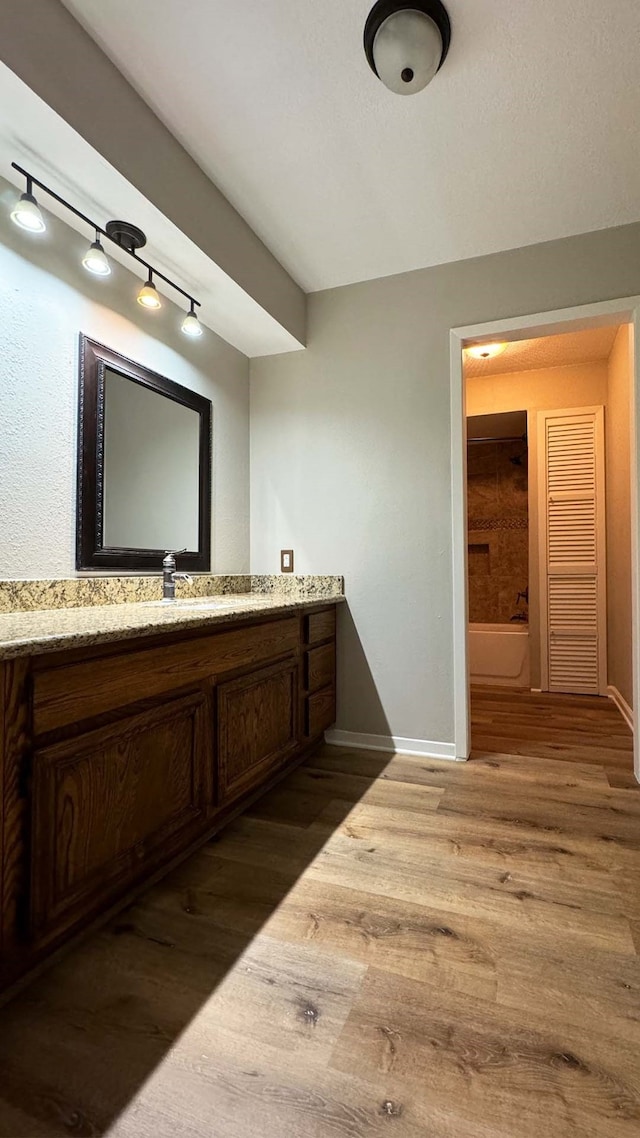 bathroom with rail lighting, wood-type flooring, and vanity