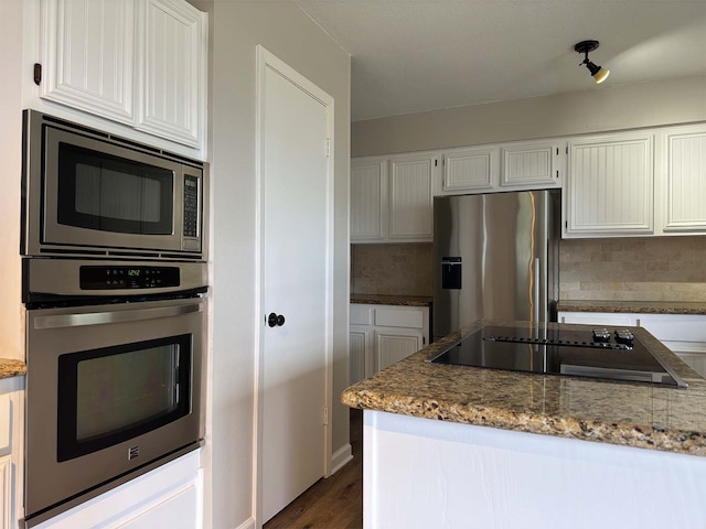 kitchen with appliances with stainless steel finishes, decorative backsplash, light stone counters, white cabinets, and dark hardwood / wood-style flooring