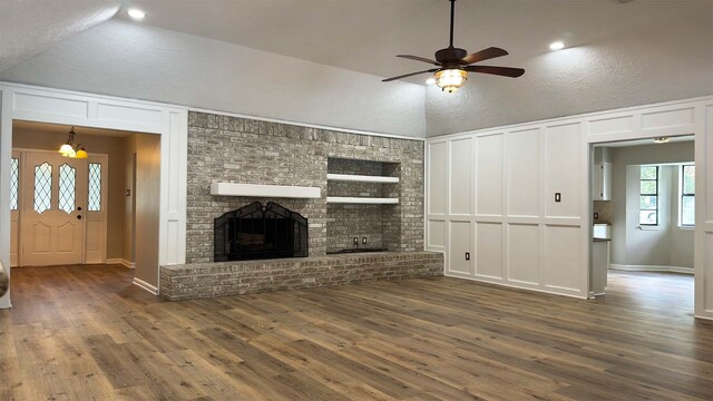 unfurnished living room featuring ceiling fan, dark hardwood / wood-style floors, a textured ceiling, and a brick fireplace