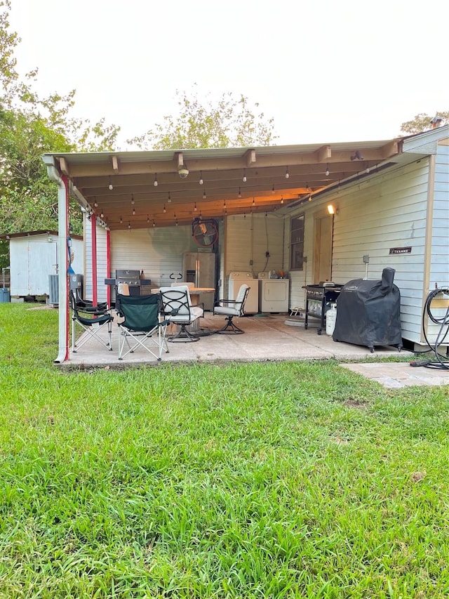 back of house with a yard, separate washer and dryer, a shed, and a patio area