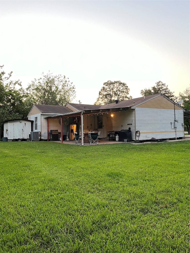 back of property featuring central AC, a lawn, and a patio area