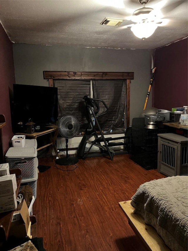 bedroom with ceiling fan, wood-type flooring, and a textured ceiling