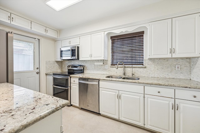 kitchen featuring white cabinetry, stainless steel appliances, sink, and light stone countertops