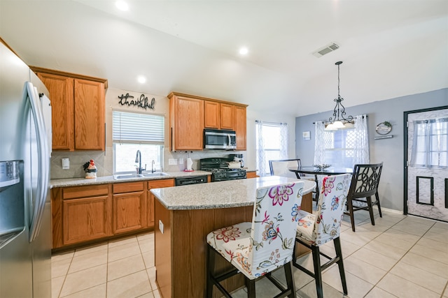 kitchen with stainless steel appliances, a kitchen island, pendant lighting, light stone countertops, and sink