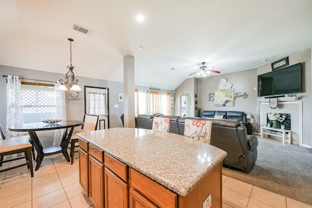 kitchen featuring light tile patterned flooring, a center island, hanging light fixtures, vaulted ceiling, and ceiling fan with notable chandelier