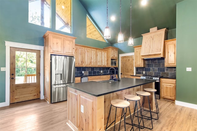 kitchen with light wood-type flooring, tasteful backsplash, appliances with stainless steel finishes, and a high ceiling