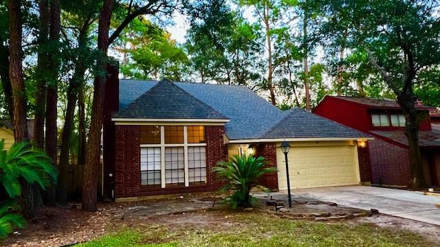 view of front of property featuring driveway, a shingled roof, a garage, brick siding, and a chimney