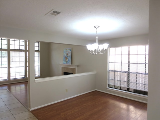 empty room featuring a textured ceiling, a notable chandelier, and hardwood / wood-style floors