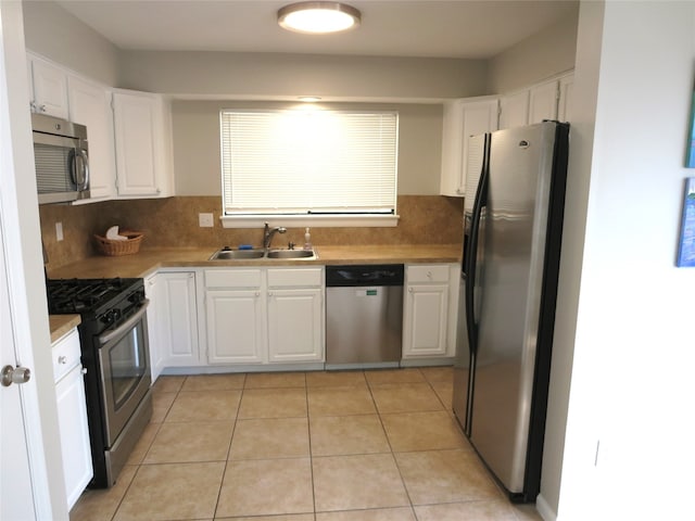 kitchen featuring tasteful backsplash, white cabinets, sink, light tile patterned flooring, and stainless steel appliances