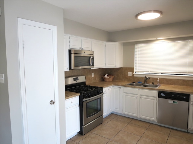 kitchen with tasteful backsplash, white cabinetry, light tile patterned floors, sink, and stainless steel appliances