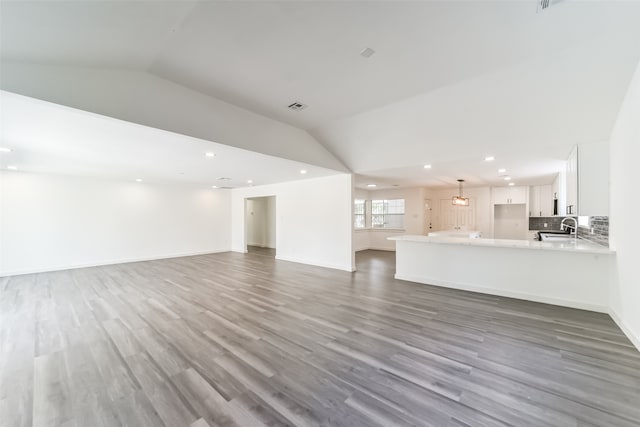 unfurnished living room with sink, vaulted ceiling, and hardwood / wood-style floors