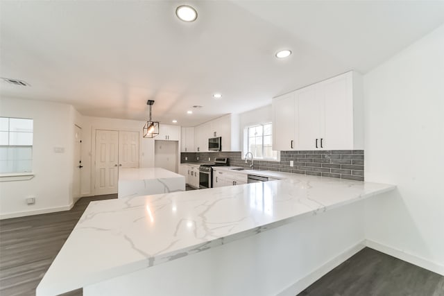 kitchen featuring stainless steel appliances, kitchen peninsula, dark wood-type flooring, and light stone countertops