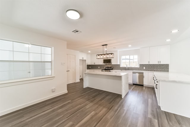 kitchen featuring stainless steel appliances, decorative light fixtures, white cabinetry, sink, and dark hardwood / wood-style flooring