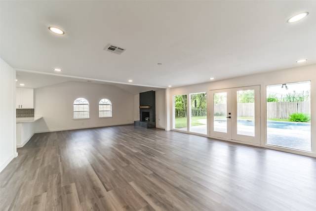 unfurnished living room featuring hardwood / wood-style flooring, a fireplace, french doors, and lofted ceiling