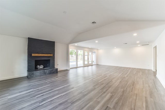 unfurnished living room featuring a large fireplace, hardwood / wood-style flooring, and lofted ceiling