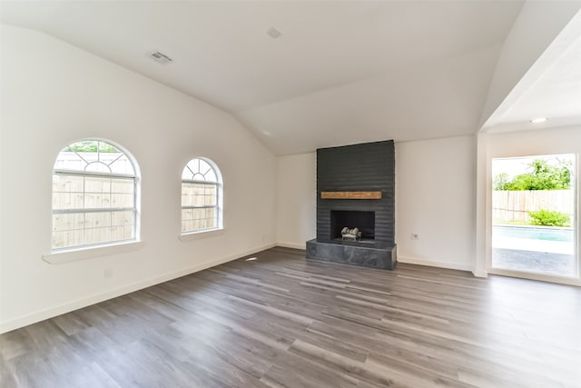 unfurnished living room featuring a fireplace, vaulted ceiling, hardwood / wood-style floors, and brick wall