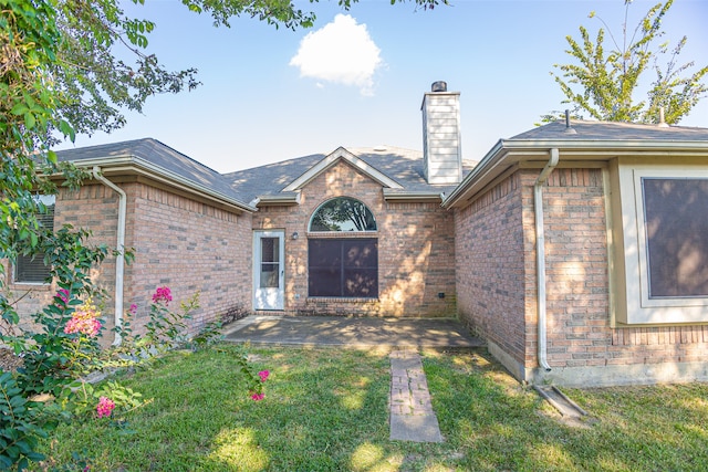 doorway to property with a patio area and a yard