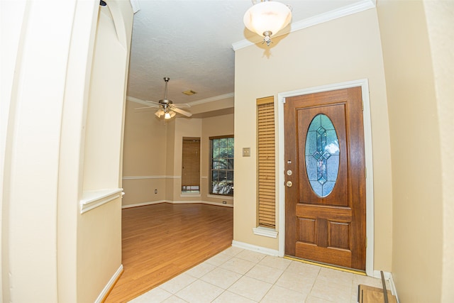 tiled entrance foyer with a textured ceiling, ceiling fan, and crown molding