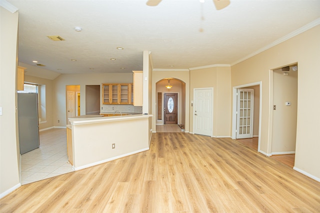 unfurnished living room featuring light wood-type flooring, ornamental molding, and ceiling fan