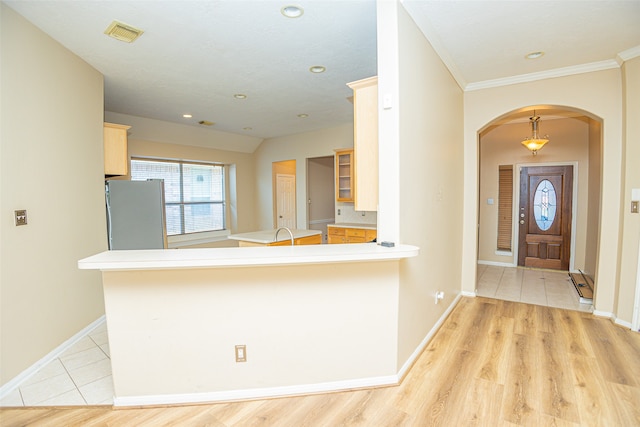 kitchen featuring light tile patterned floors, stainless steel fridge, kitchen peninsula, and ornamental molding