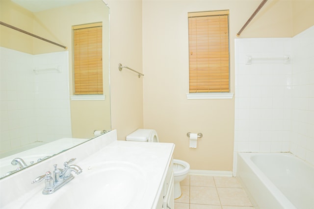 full bathroom with tile patterned flooring, tiled shower / bath, vanity, and toilet