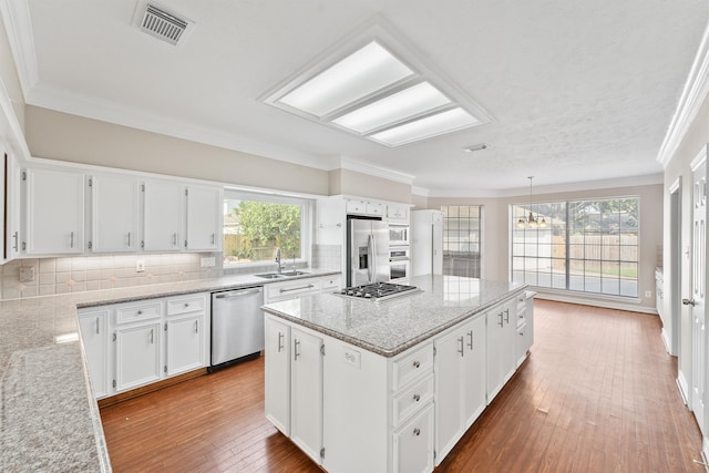 kitchen with white cabinetry, backsplash, stainless steel appliances, and ornamental molding