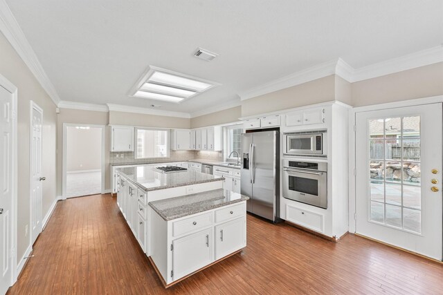 kitchen with hardwood / wood-style floors, a center island, stainless steel appliances, and white cabinetry