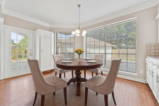 dining space featuring light wood-style floors, plenty of natural light, a notable chandelier, and ornamental molding