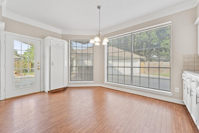 unfurnished dining area with hardwood / wood-style floors, a chandelier, and ornamental molding