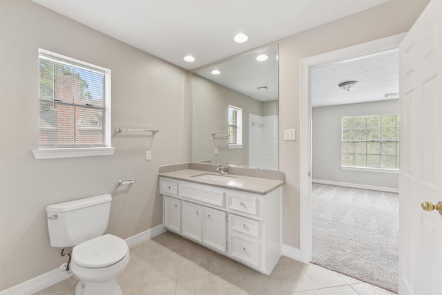 bathroom featuring tile patterned flooring, toilet, vanity, baseboards, and a shower