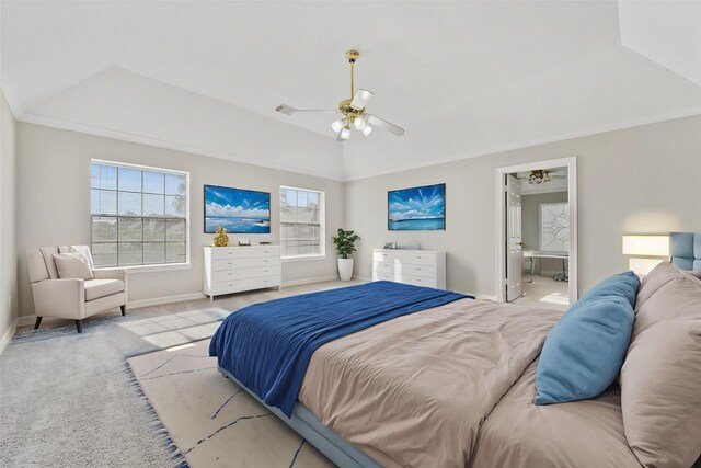 bedroom featuring crown molding, a raised ceiling, ceiling fan, light carpet, and ensuite bathroom